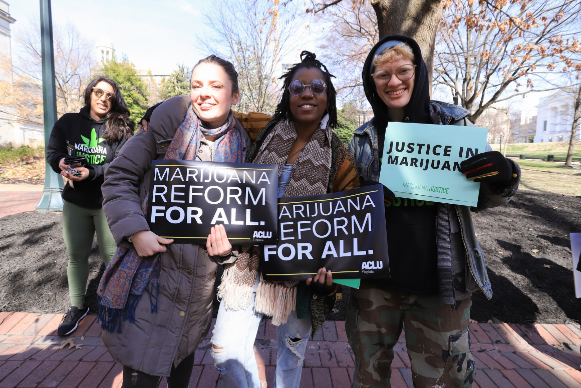 Three advocates holding signs that say "marijuana reform for all" and "justice in marijuana"