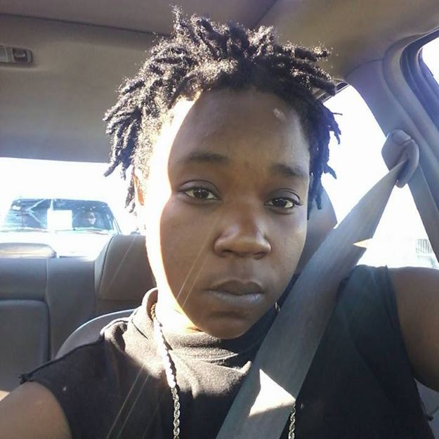 photo of India Beaty, a Black woman with short hair in locks. Photo was taken in her car.